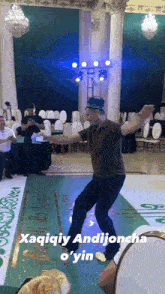 a man is dancing in a room with a sign that says ' xaqiqiy andijoncho o 'yin '
