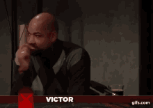 a man sitting in front of a sign that says victor on it