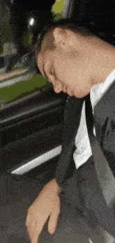 a man in a suit and tie sleeping in a car
