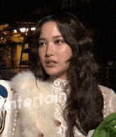 a woman wearing a white fur coat and a white top with the word entertainment on the bottom left