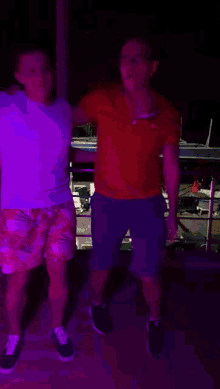 a man in a red shirt with a n on it is dancing with another man