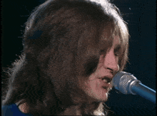 a blurry picture of a woman singing into a microphone .
