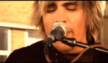 a man sings into a microphone with his eyes closed