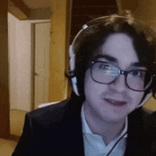 a young man wearing glasses and headphones looks at the camera