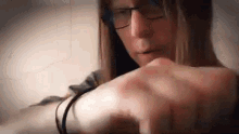 a woman wearing glasses is pointing at her wrist .