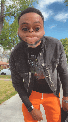 a man wearing a black jacket and orange pants making a face