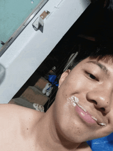 a young man without a shirt is taking a selfie with cake on his face