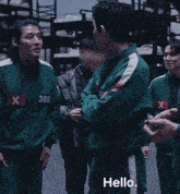 a man in a green uniform with a red x on his chest talks to another man