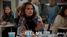 a woman sitting at a table with a netflix logo on the bottom