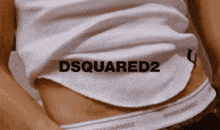 a woman wearing a white tank top with dsquared2 written on it