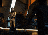a man in a superhero costume stands next to another man in a black shirt with kepler written on the bottom