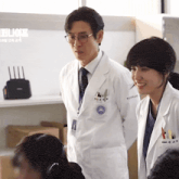 a man and a woman in lab coats are standing in front of a sign that says ' 19 ' on it