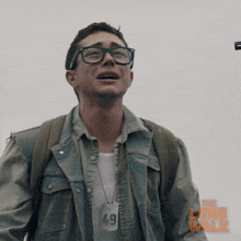 a man wearing glasses and a denim jacket with the long walk written on it