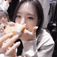 a girl is eating a donut with powdered sugar