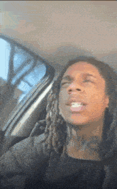 a young man with dreadlocks is sitting in a car .