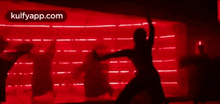 a silhouette of a person dancing in front of a red light .