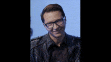 a man wearing glasses and a leather jacket is smiling and looking at the camera .