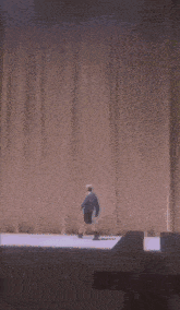 a man in a blue shirt and shorts is standing behind a brown curtain