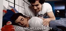 two men are sleeping in a bed and one of them is putting his hand on the other 's shoulder .