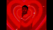 a man is standing in front of a heart shaped projection .
