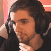 a man with a beard wearing headphones is sitting in a chair .