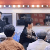 a group of people are sitting in a room with a man standing in front of them .