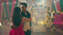 a man and a woman are dancing in a room filled with balloons .