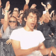 a man in a white shirt is dancing in a crowd
