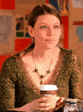 a woman sitting at a table with a cup of coffee in her hand