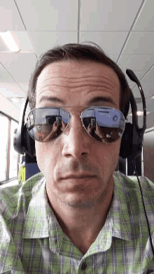 a man wearing sunglasses and headphones takes a selfie with his phone