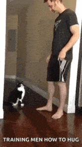 a man is teaching a cat how to hug .