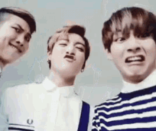 a group of three young men are making funny faces for the camera .