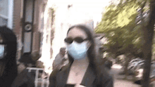 a woman wearing a mask and sunglasses walking down a street