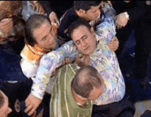 a group of men are fighting each other and one of them is wearing a tie dye shirt .