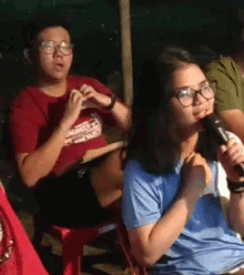 a woman with glasses is holding a microphone in front of her face