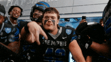 a football player wearing a memphis jersey points at something