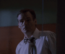 a man in a white shirt and tie is waving his hand in the dark