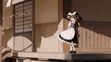 a doll wearing a black and white dress and hat is standing on a porch
