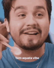 a man with a beard is holding a spoon in his mouth and the words tem aquela vibe are above him