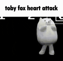 a stuffed animal is laying on its back on a black background with the words `` toby fox heart attack '' written above it .