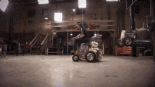 a man is riding a lawn mower in a garage with a stop sign on the wall behind him