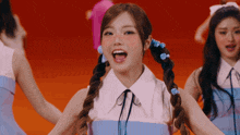 a girl with pigtails and blue ribbons in her hair is smiling