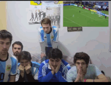 a group of young men are watching a soccer game with a new york city sign hanging on the wall behind them