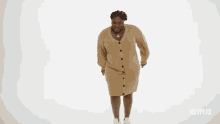 a woman in a sweater dress is dancing in front of a white background with netflix written on it