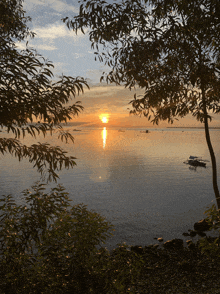 a sunset over a body of water with boats in the distance