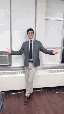 a man in a suit and tie is standing in front of a window