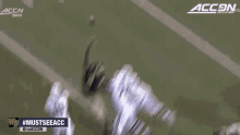 a football player catches a ball with the accn logo behind him