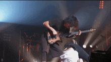a man is playing a bass guitar on a stage with the letter d below him