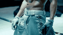 a shirtless man is holding a sword in his hands