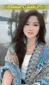 a woman wearing a blue jacket and a white shirt is standing in front of a lake .